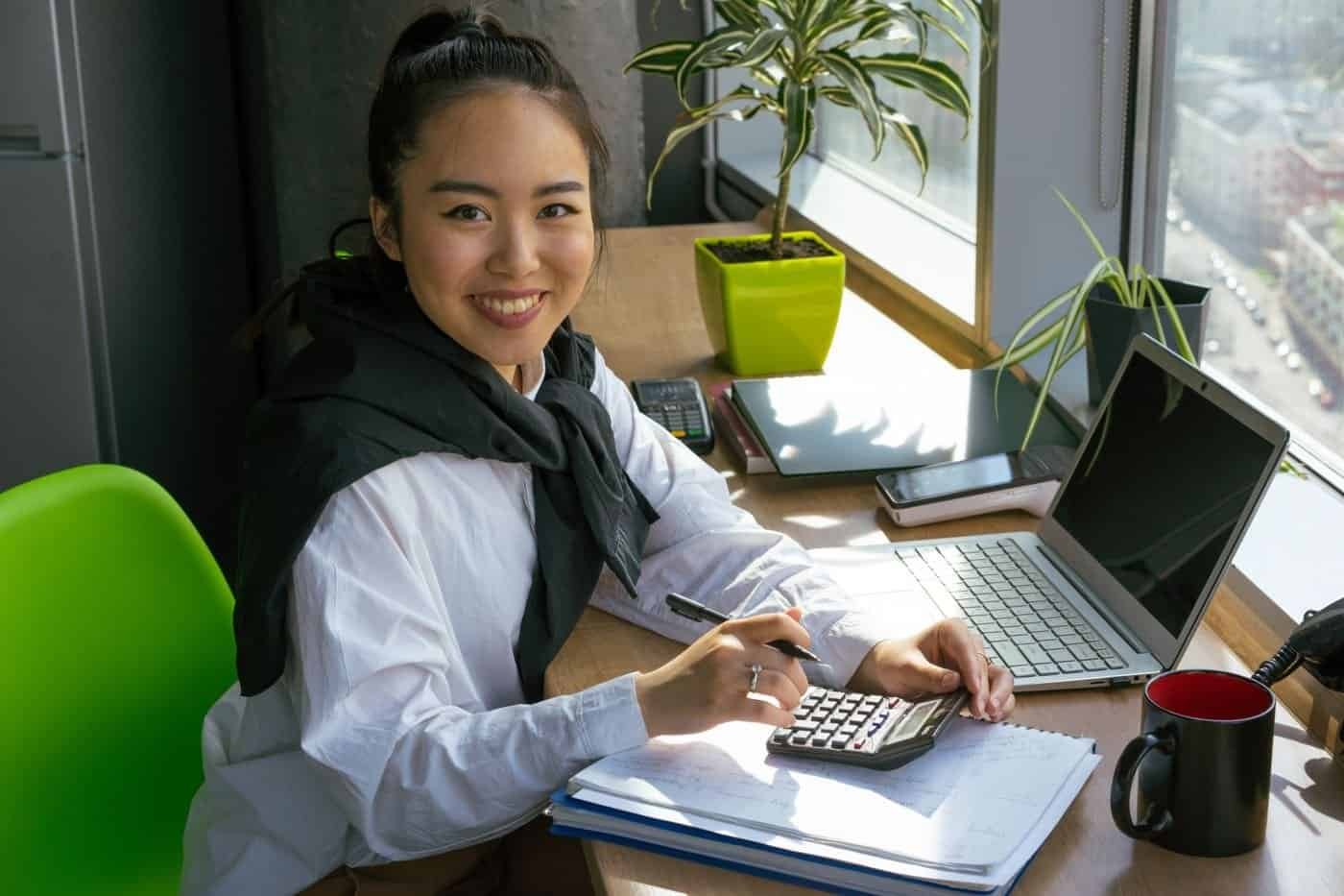 Asian businesswoman in Singapore office using a calculator for payroll or CPF calculations