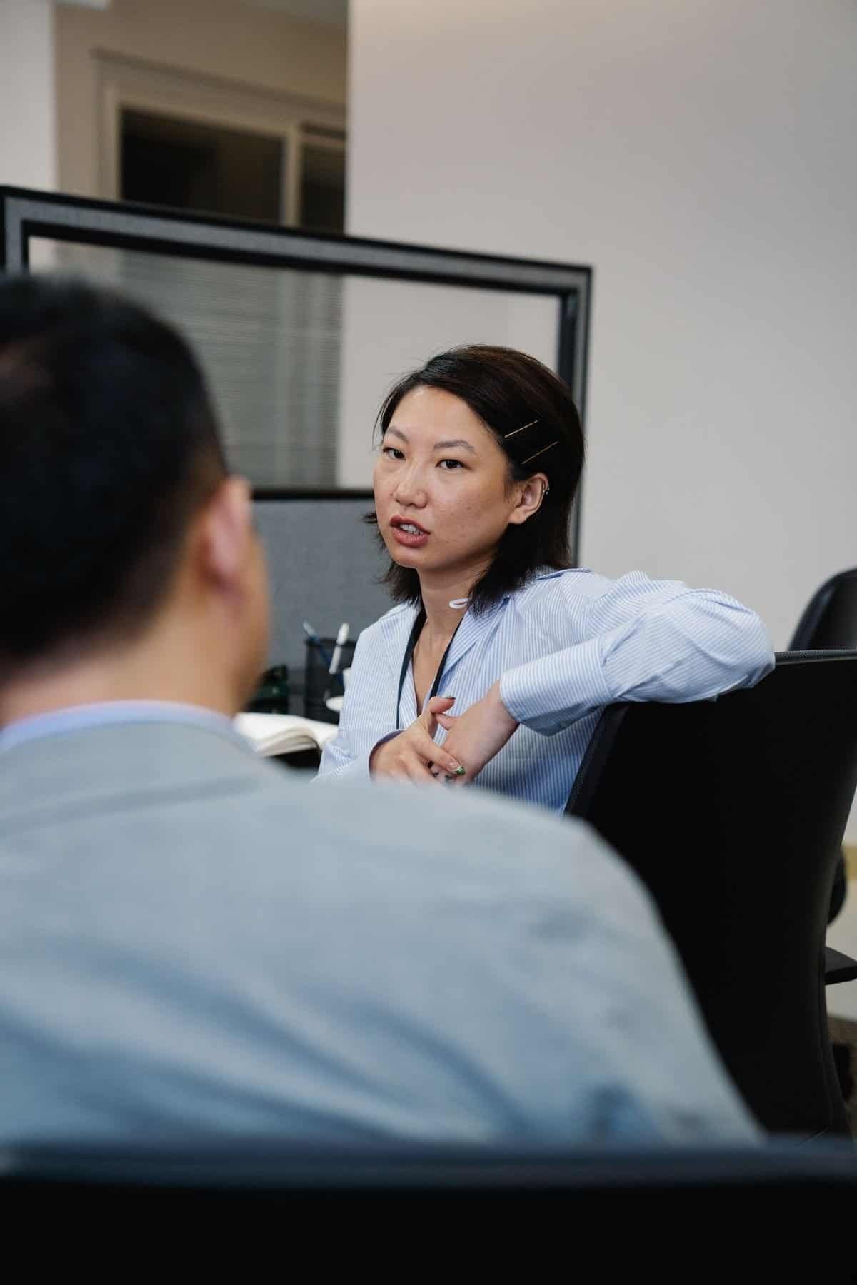 Asian woman speaking in a workplace discussion, representing experienced workers and age-inclusive hiring practices